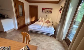 A cozy room with a bed and a seating area. There is a table and large windows that let in plenty of light.