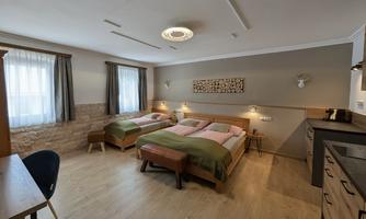 A cozy room with two single beds and wooden floor.  
High windows provide plenty of daylight and an inviting atmosphere.