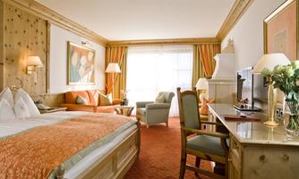 A cozy hotel room with a double bed and elegant decor. The room features natural light sources and a pleasant atmosphere.