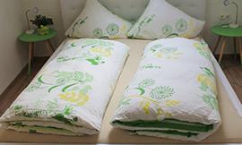 A cozy bedroom with a large bed and freshly made blankets. Next to the bed are two small nightstands with lamps.