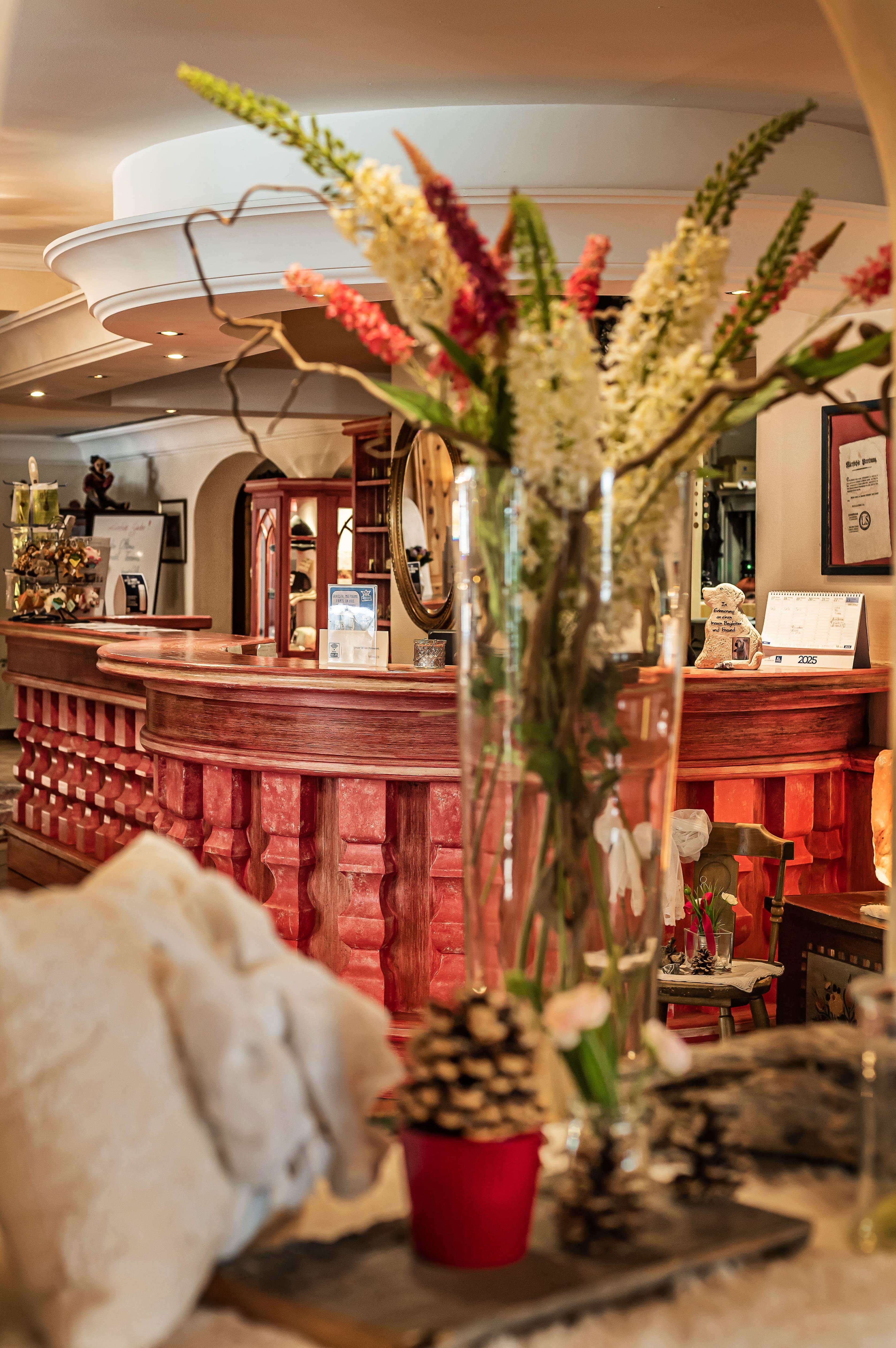 An inviting interior with a red counter and lush flower arrangements. Cozy decorative elements create a warm atmosphere.