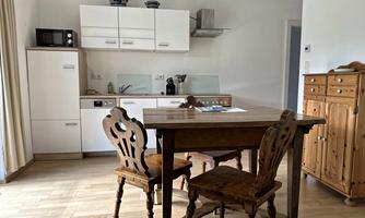A modern kitchen with a wooden dining table and chairs. The decor is bright and friendly designed.