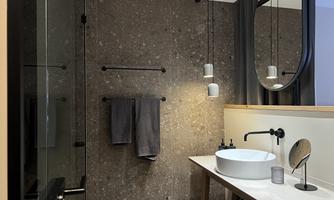 A modern bathroom with elegant furnishings. It features a large shower, a sink, and a stylish wall design.