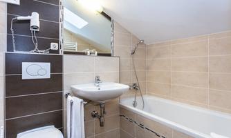 A modern bathroom with a bathtub and a sink. The walls are brightly tiled and the lighting is pleasant.