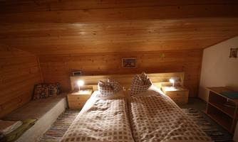 A cozy bedroom with two separate beds and wooden ceilings. The atmosphere is warm and inviting, perfect for relaxation.