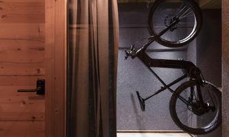 A modern room with a hanging e-bike and wooden paneling. The room is minimalist and well-organized.