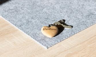 A keychain with a heart-shaped keyring lies on a gray background. The pendant has the inscription "Beethoven".