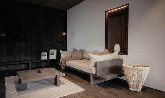 A modern living room with a minimalist sofa and a wooden coffee table. Soft colors and stylish lighting create an inviting atmosphere.