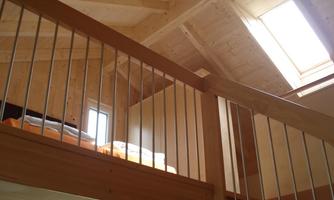 A modern wooden interior with a view of a gallery.  
Large windows allow for plenty of natural light.