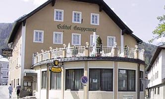 A charming inn with a round shape and a balcony. The facade is in gentle colors and surrounded by a quiet street.