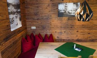A cozy room with wood-paneled walls and a table. Red seat cushions and a modern lamp create a pleasant atmosphere.
