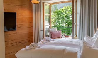 A cozy room with two beds and a large window. The view into the greenery creates a relaxed atmosphere.