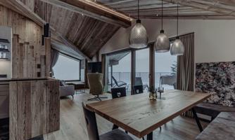 A stylish interior with wood paneling and modern lighting elements. The dining area offers a view of nature through large windows.
