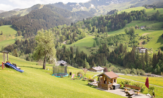 An idyllic landscape with gentle hills and trees. In the foreground, there are leisure equipment and a small hut.