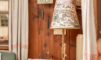 A cozy room with two armchairs and a decorative table. A clock is hanging on the wall and some pretty plates are on display.