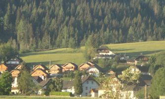 A picturesque landscape with traditional wooden houses. In the background, green meadows and wooded hills stretch out.