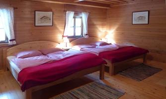 A cozy room with two beds and wooden paneling. The windows let in plenty of daylight and create an inviting atmosphere.