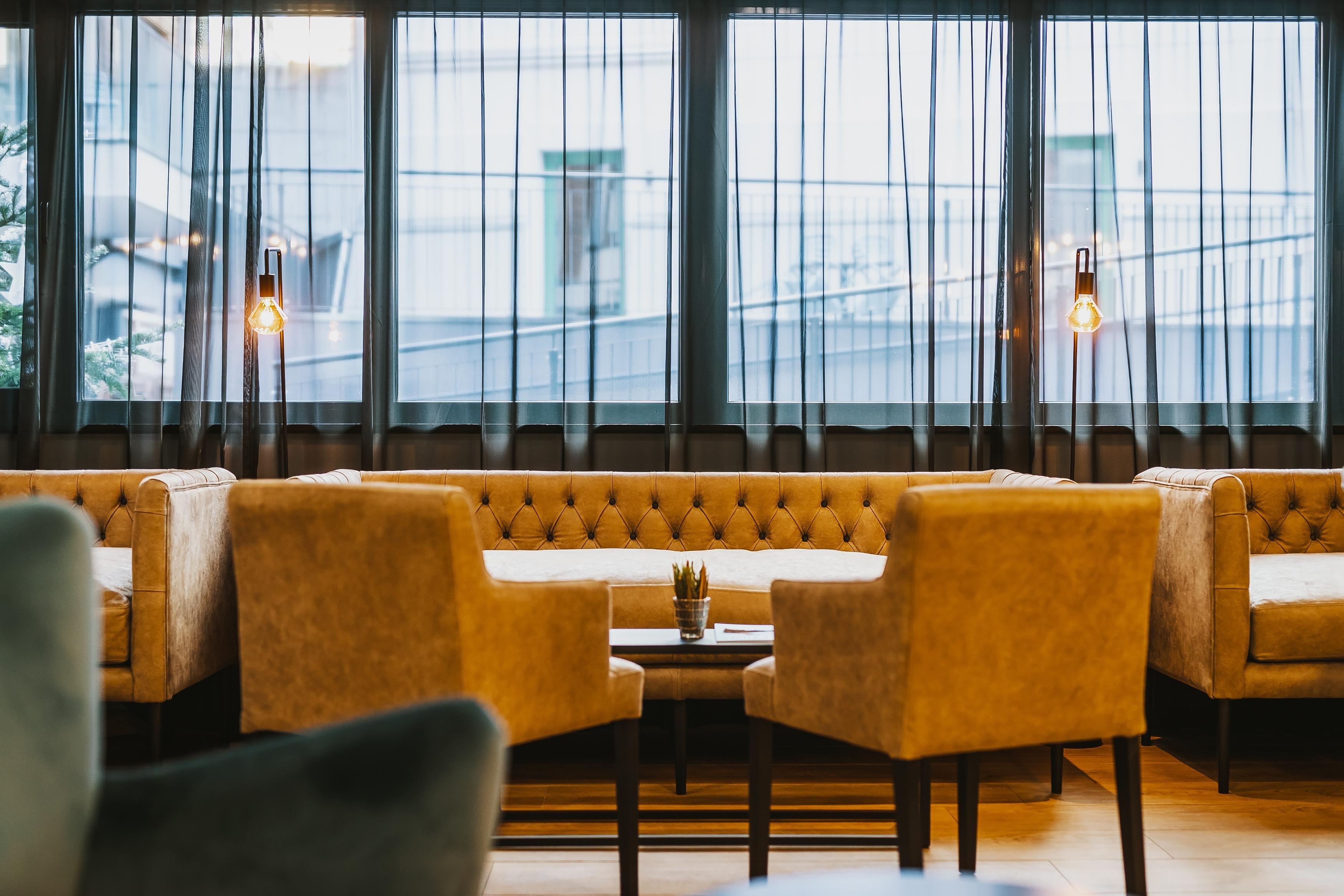 An elegant interior with comfortable armchairs and a low table. Large windows let in plenty of light and offer a view outside.