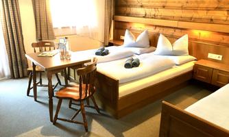A cozy room with two beds and wooden walls. Water and towels are ready at the table.