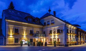 A pretty building in the evening light, tastefully illuminated. The architecture is traditional with flower boxes and an inviting entrance area.