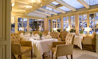 An elegant restaurant with large windows and cozy seating. The table is festively set and decorated.