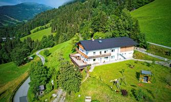 A beautiful house in a green landscape, surrounded by trees and hills. The location offers a peaceful atmosphere and a view of nature.