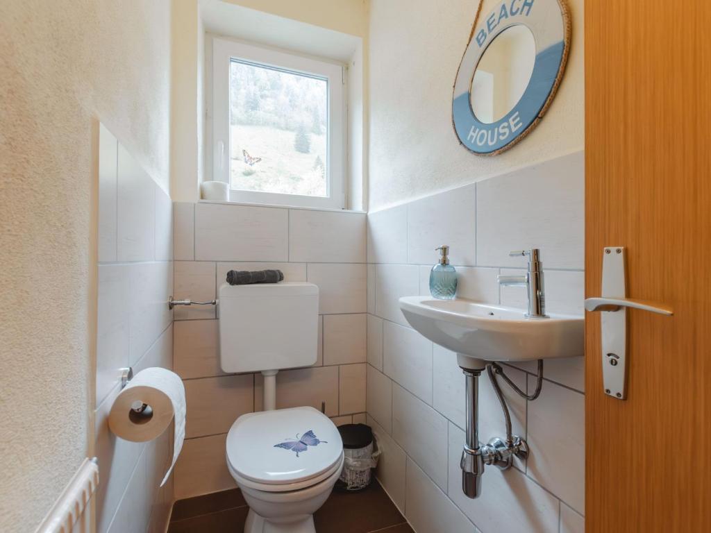 <p>Small, bright WC with a window, a wall mirror in maritime style, a small sink and a toilet with white tiled covering.</p>