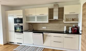 A modern kitchen with white cabinets and a black countertop. The wooden floors and decorative elements give the room a warm atmosphere.