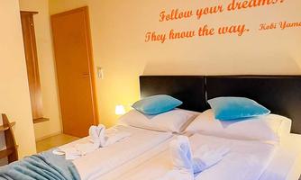 A bright room with two beds and blue cushions. On the wall is the phrase: "Follow your dreams. They know the way."