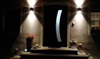 An entrance area with a lit door and steps. The atmosphere is cozy and inviting at night.