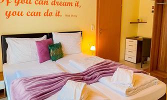 A cozy bedroom with two beds and a warm color scheme. On the wall is an inspiring quote.