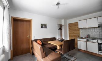 A modern living room with a dining area and a kitchenette. The decor is bright and inviting, perfect for social meals.