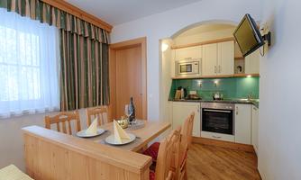 A cozy kitchen with wooden furniture and a dining area. The decor is modern and inviting, with a window that lets in daylight.