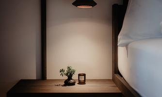 A stylish bedroom with a bright nightstand. On the table, there is a small plant and a scented candle.