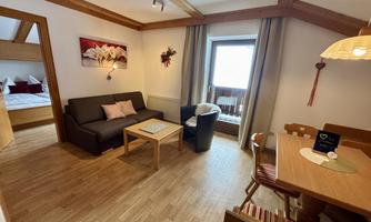 A cozy living room with a sofa and a dining table. Large windows provide plenty of light and offer a beautiful view.
