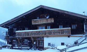 A traditional wooden house in the winter snow. The sky is grey and light snow is falling.