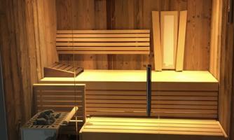 A modern wooden sauna with several benches and soft lighting. In the foreground, a heating appliance is visible.
