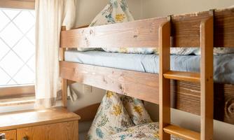 A cozy room with a wooden loft bed. The beds are decorated with colorful pillows and blankets.