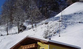 A charming yellow house in the snow, surrounded by snow-covered trees. The sky is clear and blue, creating a winter idyll.