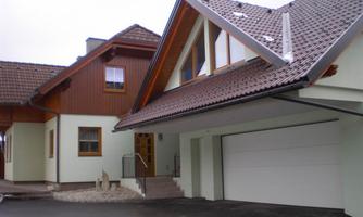 A modern house with a combination of wood and render facade. The garage is spacious, and the entrance stairway looks inviting.
