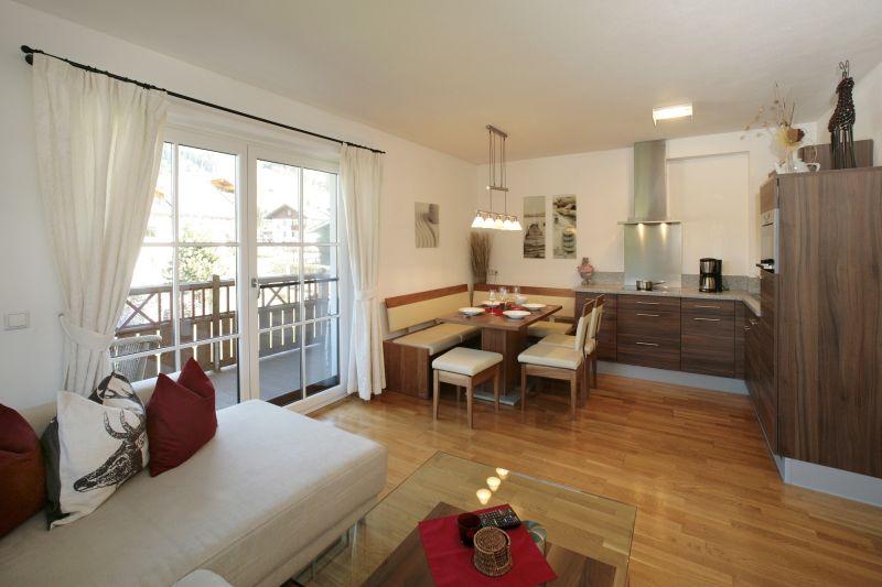 A modern living kitchen with hardwood floor and plenty of natural light. The room is cozily furnished with a sofa and a dining table.