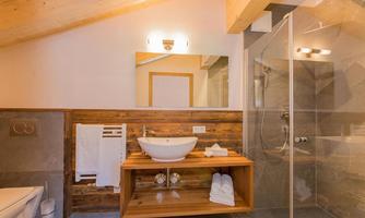 A modern bathroom with a glass shower and a stylish sink. The wood paneling and soft lighting create a warm atmosphere.