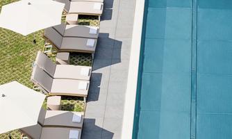 An elegant pool with beige loungers and sun umbrellas. The surroundings are well-maintained and invite relaxation.