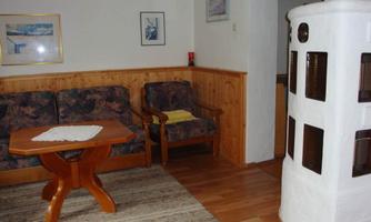 A cozy living space with wood paneling and a round table. On the right side, there is a white stove.