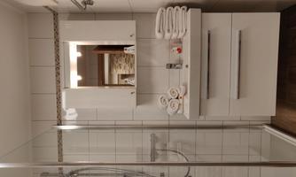 A modern bathroom with a glass shower and a white sink. Neatly folded towels are ready.
