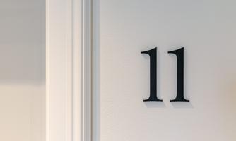 A white wall with the number 11 in black lettering. The number is modern and clearly visible.