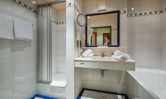A modern bathroom with a shower, sink, and bathtub. The walls are tiled and adorned with colorful accents.