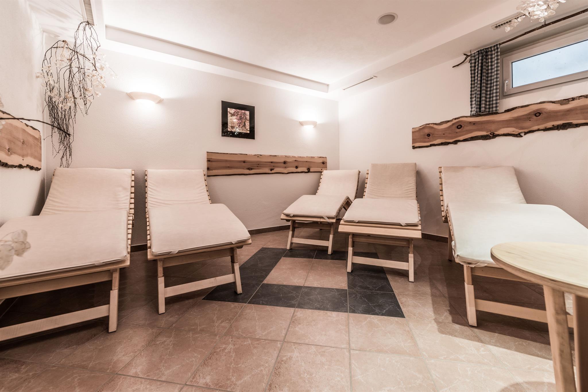 <p>A quiet relaxation room with wooden loungers. The walls are bright and there is soft lighting for a relaxing atmosphere.</p>