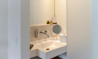 A modern bathroom with an elegant sink and mirror. The walls are light, and there are decorative elements on the vanity.