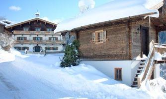 A snow-covered mountain village with traditional wooden houses. The landscape is peaceful and picturesque under a clear blue sky.